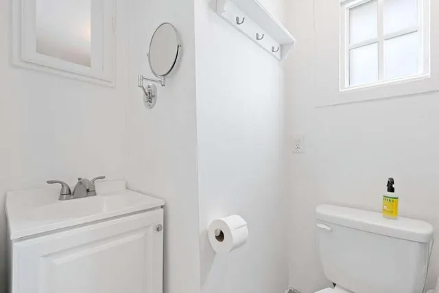 a bathroom with a granite countertop sink a toilet and a mirror