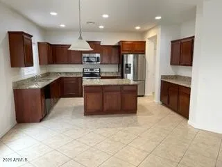 a large kitchen with stainless steel appliances granite countertop a stove top oven a sink and a refrigerator