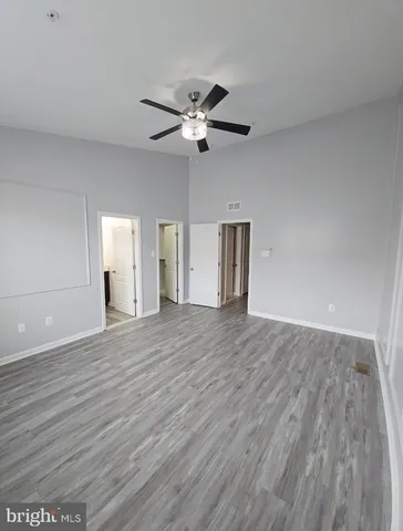 a view of an empty room with a ceiling fan and wooden floor