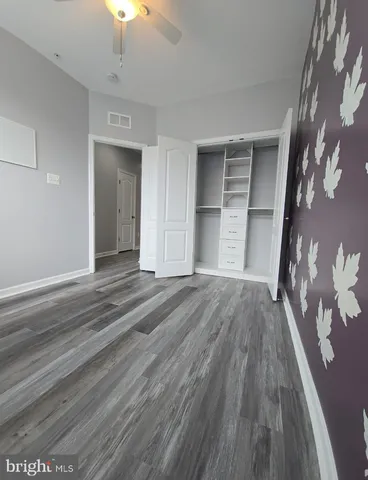 a view of an empty room with wooden floor and a chandelier