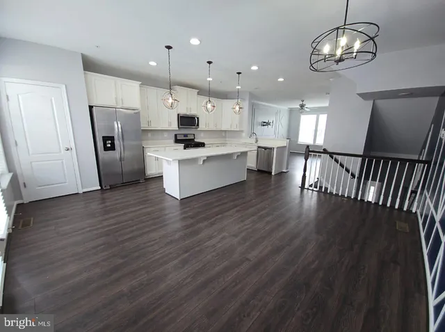 a kitchen with stainless steel appliances granite countertop a refrigerator microwave and wooden floor
