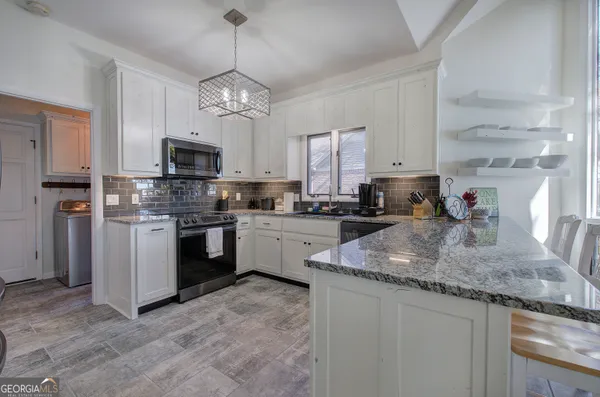 a kitchen with granite countertop white cabinets and a stove