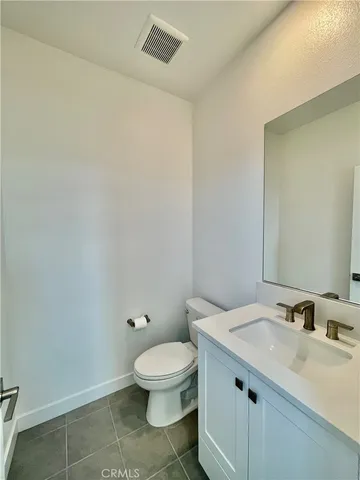 a bathroom with a granite countertop toilet a sink and a mirror