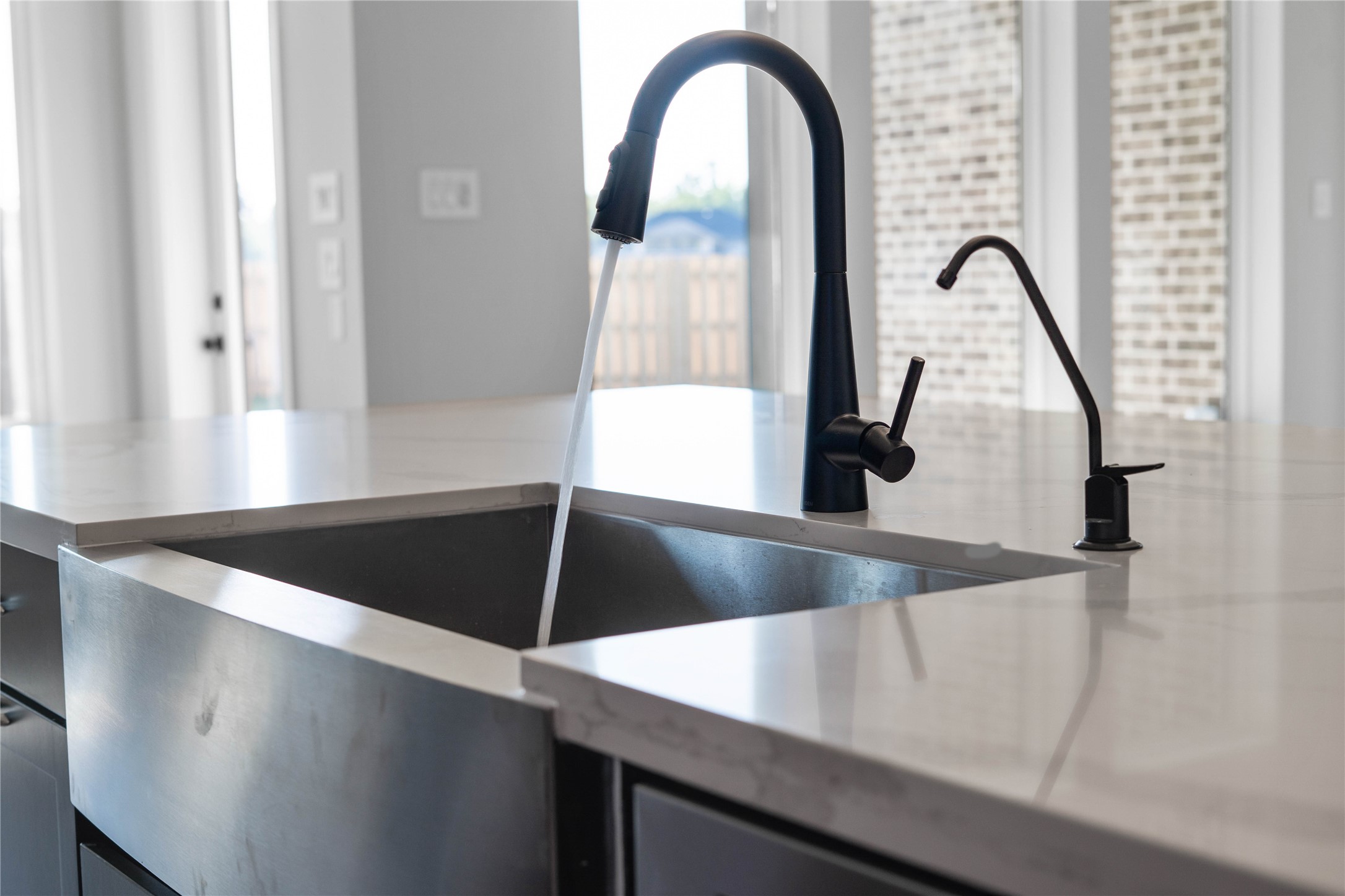 2114 Rowl Street Montgomery, TX 77316 - Photo 28 of 50 The center island is anchored by a massive stainless steel apron-front farmhouse sink, blending industrial durability with modern style. This high-capacity basin is paired with a matte black gooseneck pull-down faucet for maximum versatility. Adding an extra layer of luxury is the dedicated filtered water dispenser, ensuring pure hydration at your fingertips.