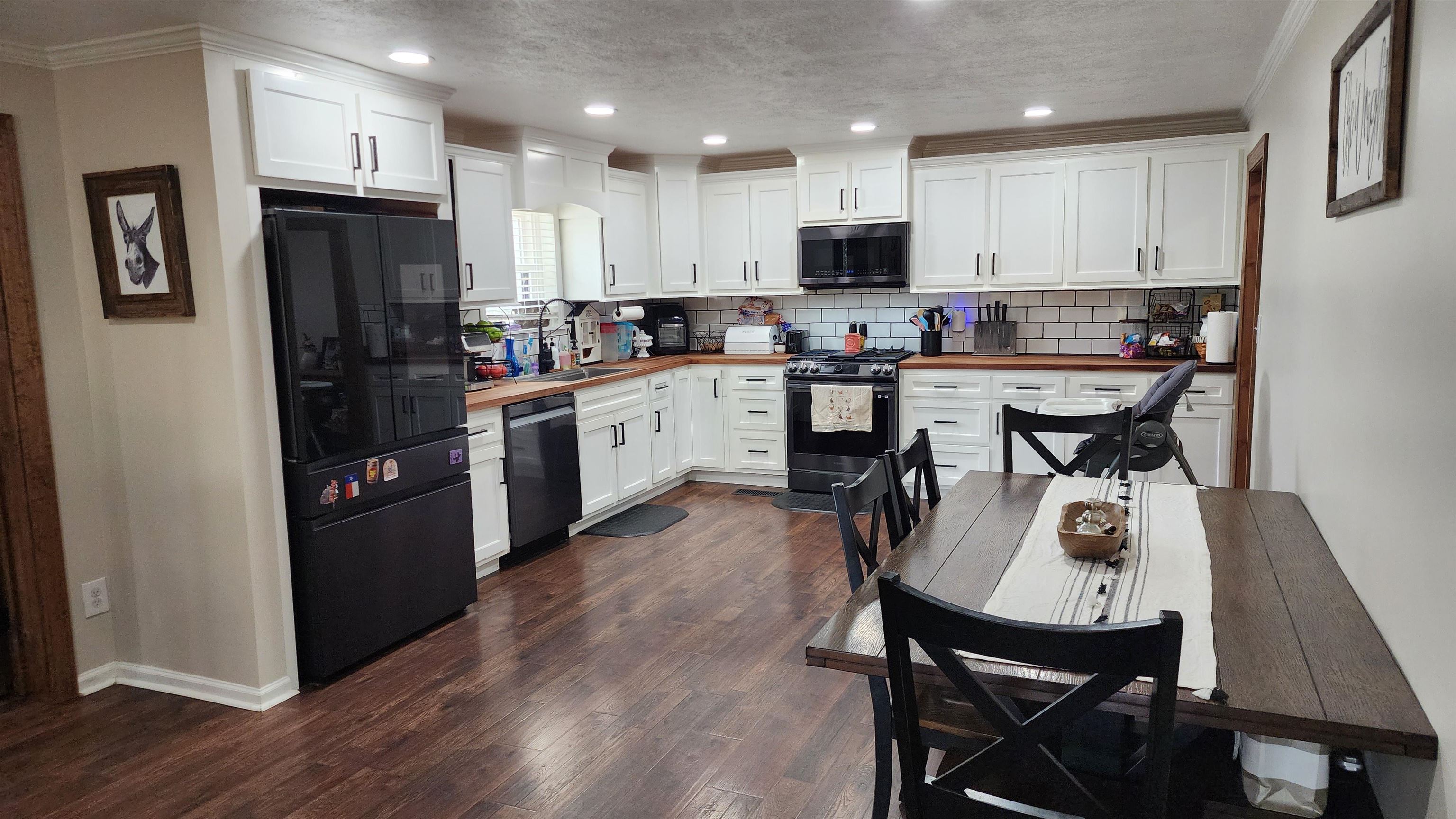 948 George Weakley Road Dyersburg, TN 38024 - Photo 4 of 31 a kitchen with stainless steel appliances granite countertop a refrigerator a stove top oven a sink dishwasher and a dining table with wooden floor