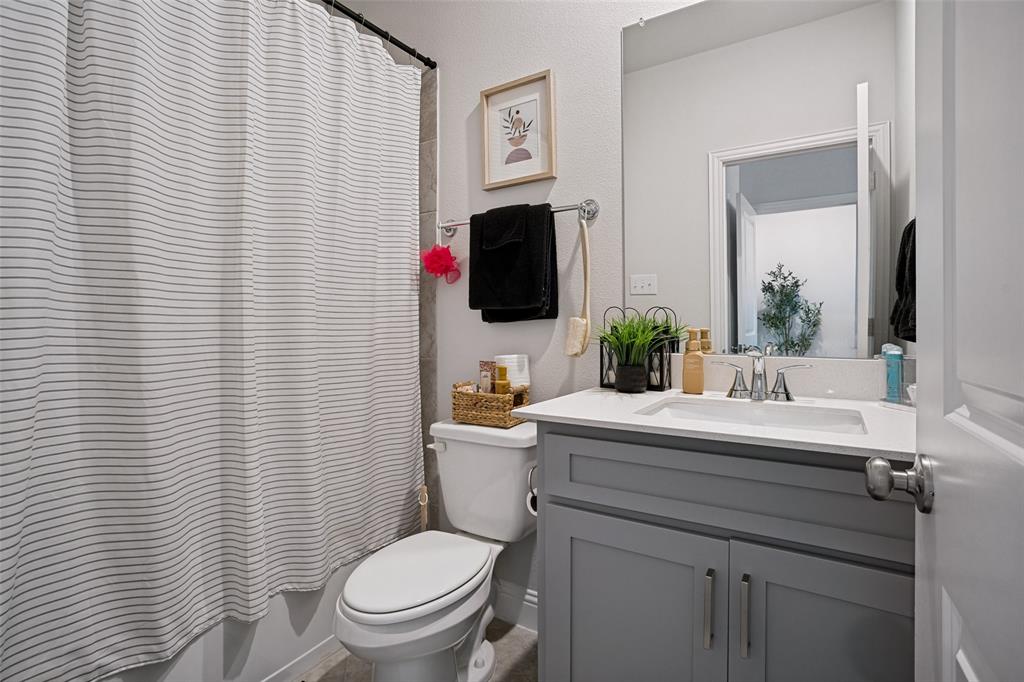 3115 Giovanni Point Princeton, TX 75407 - Photo 14 of 26 Bathroom featuring a single vanity with gray cabinetry and a white countertop, a white toilet, and a shower with a striped curtain