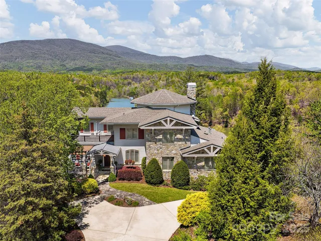a view of a big house with a big yard and large trees