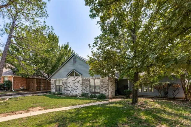 a view of a house with a yard and large tree