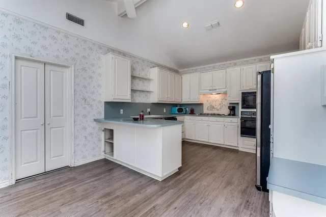 a kitchen with wooden floors white appliances and cabinets
