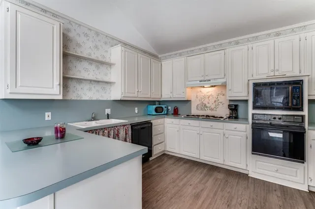a kitchen with granite countertop white cabinets and stainless steel appliances