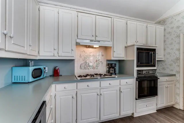 a kitchen with stainless steel appliances granite countertop white cabinets and sink