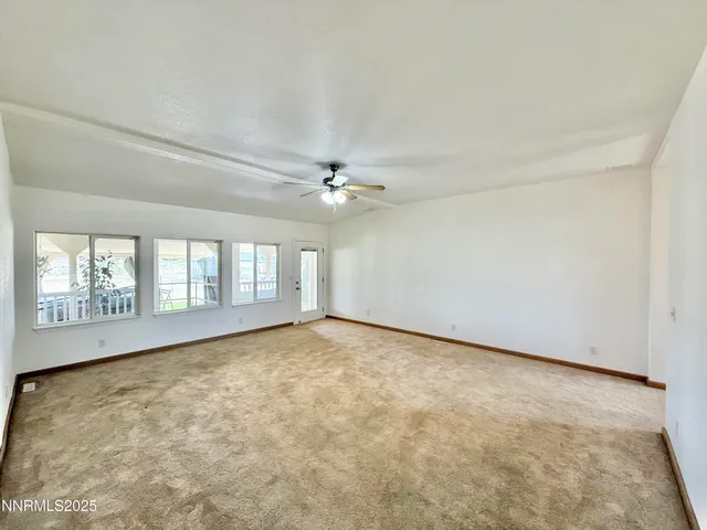 an empty room with windows and ceiling fan