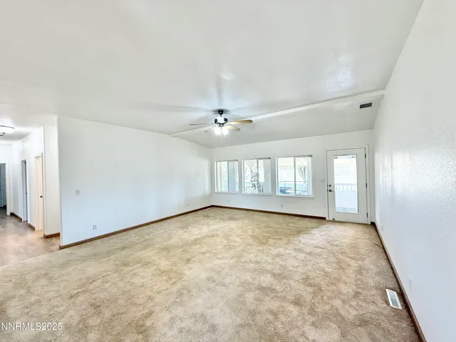 an empty room with a ceiling fan and window