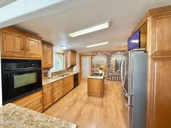 a kitchen with stainless steel appliances granite countertop a refrigerator a stove and a sink with wooden floor