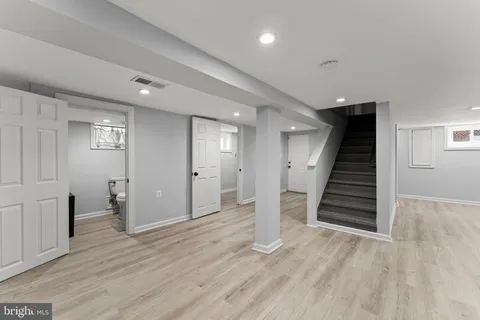 a view of an empty room with wooden floor and stairs