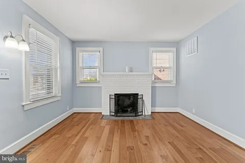 an empty room with wooden floor fireplace and windows