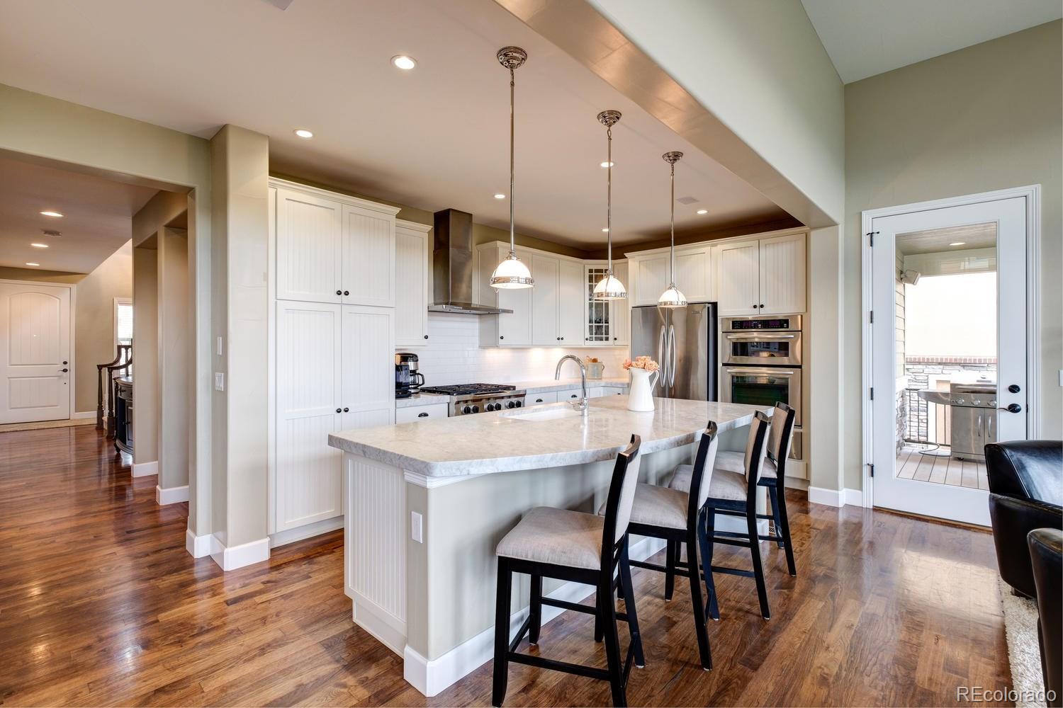10711 Sundial Rim Road Highlands Ranch, CO 80126 - Photo 1 of 35 a kitchen with stainless steel appliances a table chairs refrigerator and wooden floor
