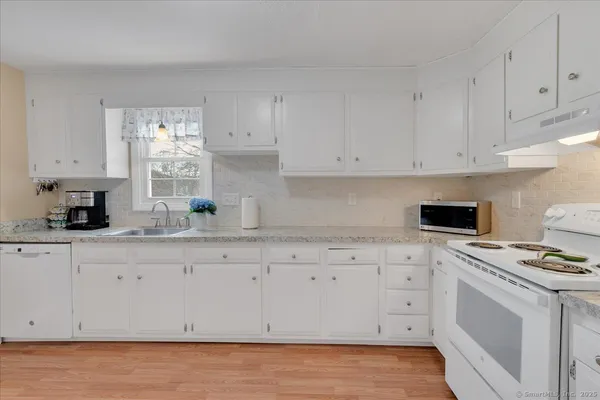 a kitchen with granite countertop white cabinets and white appliances