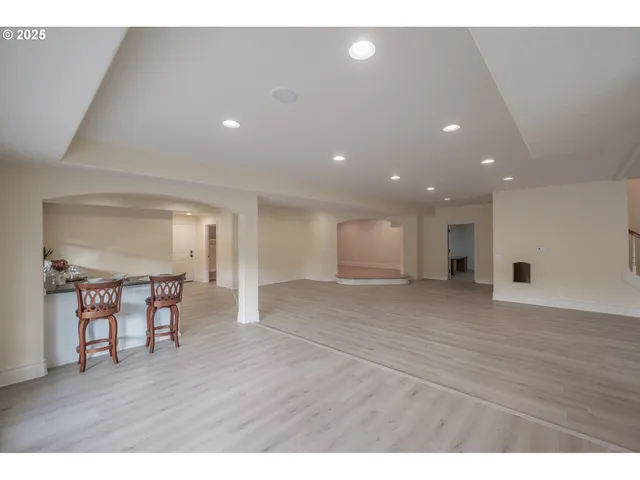 a kitchen with granite countertop a stove a sink a refrigerator and white cabinets with wooden floor