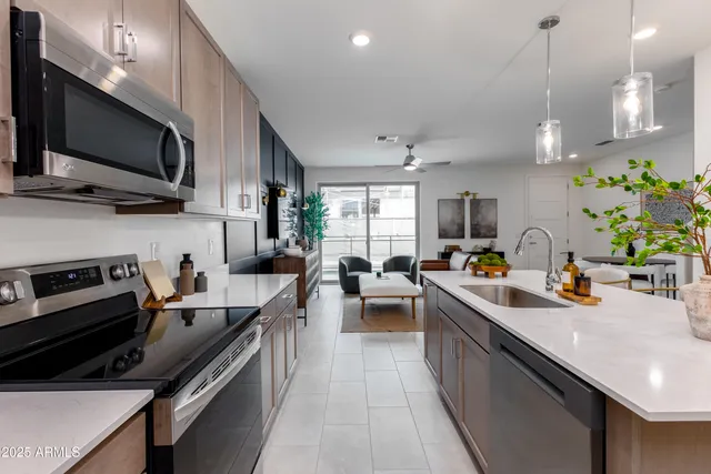 a kitchen with stainless steel appliances a sink dishwasher a stove top oven a refrigerator with wooden floor and cabinets