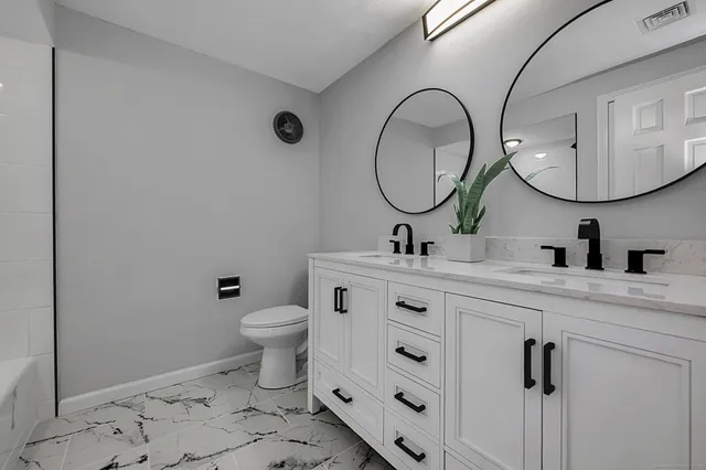a bathroom with a double vanity sink toilet and a mirror