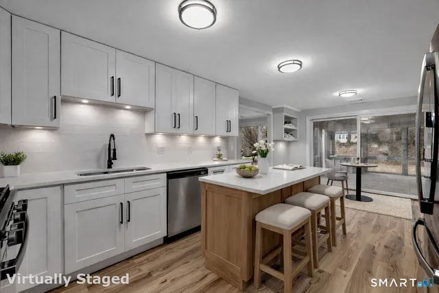 a kitchen with white cabinets appliances and chairs