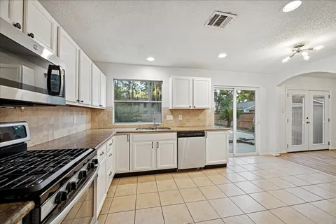 a kitchen with stainless steel appliances granite countertop a stove top oven a sink a counter space and cabinets