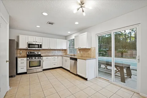 a kitchen with white cabinets and appliances