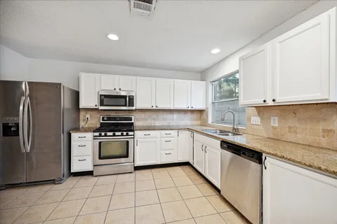 a kitchen with white cabinets stainless steel appliances and a sink