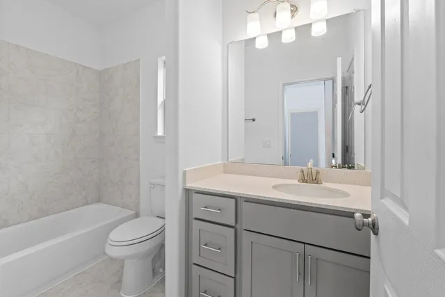 a bathroom with a sink a toilet a mirror a vanity and bathtub