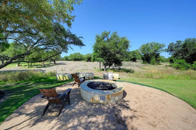 a view of a backyard with table and chairs potted plants and tree