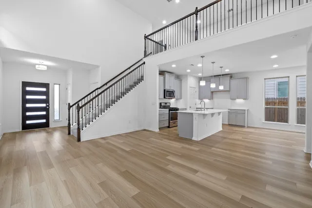 a view of kitchen with kitchen island wooden floor and stainless steel appliances