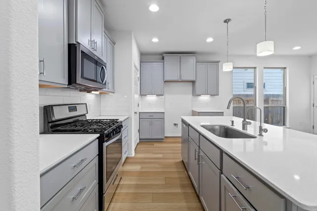 a kitchen with stainless steel appliances granite countertop a sink a stove and a wooden floors