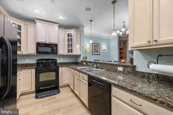 a kitchen with granite countertop a sink white cabinets and stainless steel appliances