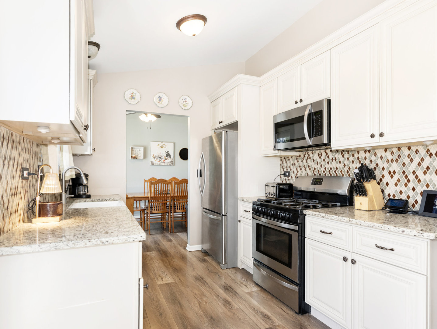 1400 Bar Harbour Road Aurora, IL 60504 - Photo 6 of 25 a kitchen with stainless steel appliances kitchen island granite countertop a stove top oven a sink a refrigerator white cabinets and wooden floor