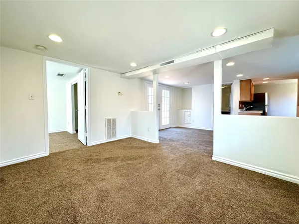 a view of an empty room and kitchen view