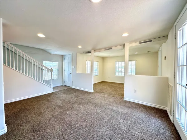 a view of an empty room and kitchen with furniture