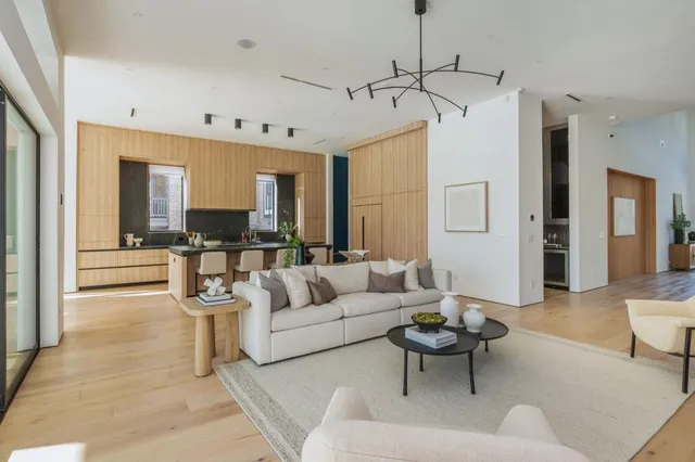 a living room with furniture kitchen view and a chandelier