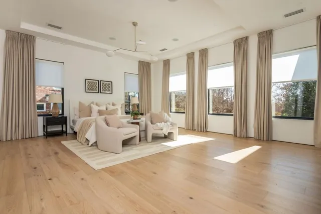 a living room with furniture large windows and wooden floor