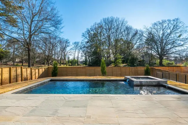 a view of swimming pool with trees and wooden fence