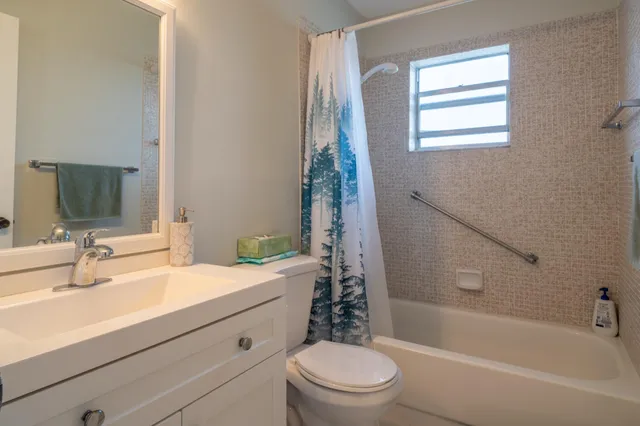 a bathroom with a sink a toilet a mirror a bathtub and shower