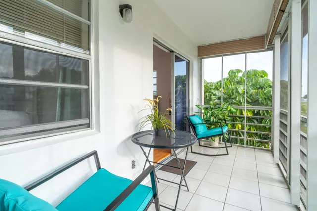 a view of a porch with chairs and potted plants next to a window