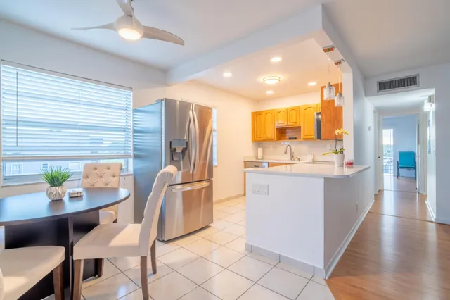 a large kitchen with stainless steel appliances kitchen island granite countertop a table chairs in it and a window