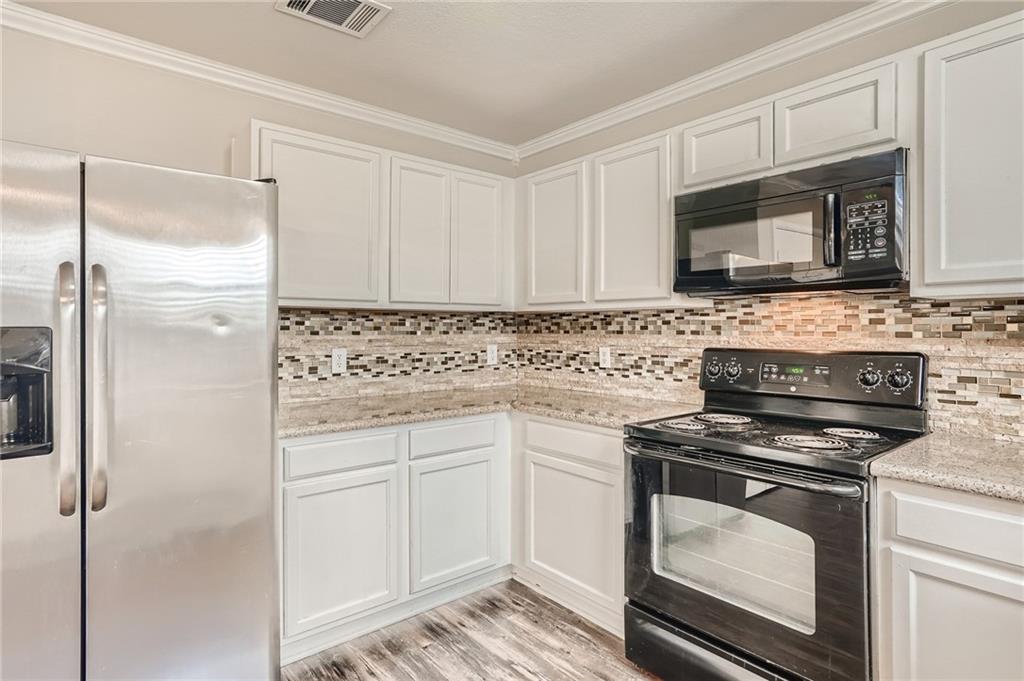 612 Copper Court Jarrell, TX 76537 - Photo 10 of 27 a kitchen with white cabinets and stainless steel appliances