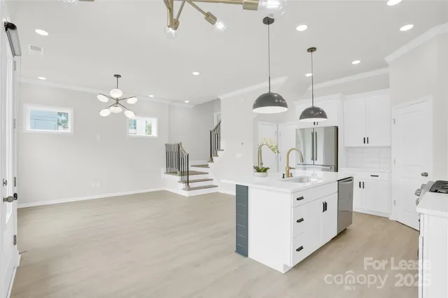 a large room with kitchen island a large island a sink stainless steel appliances and cabinets