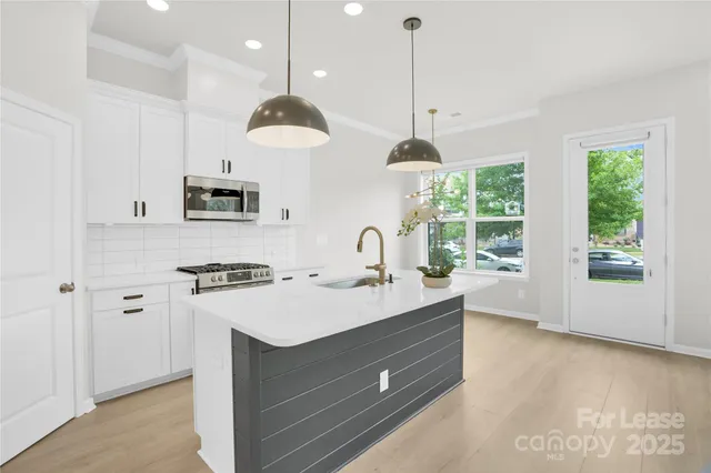 a kitchen with kitchen island a stove a sink a center island and windows