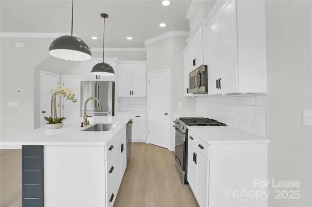 a kitchen with stainless steel appliances granite countertop a sink a stove and a wooden floors