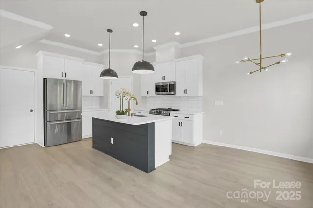 a kitchen with stainless steel appliances kitchen island granite countertop a refrigerator and a sink