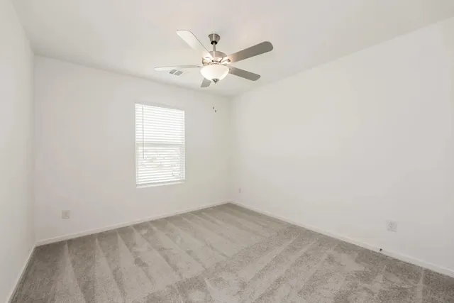 an empty room with ceiling fan and window