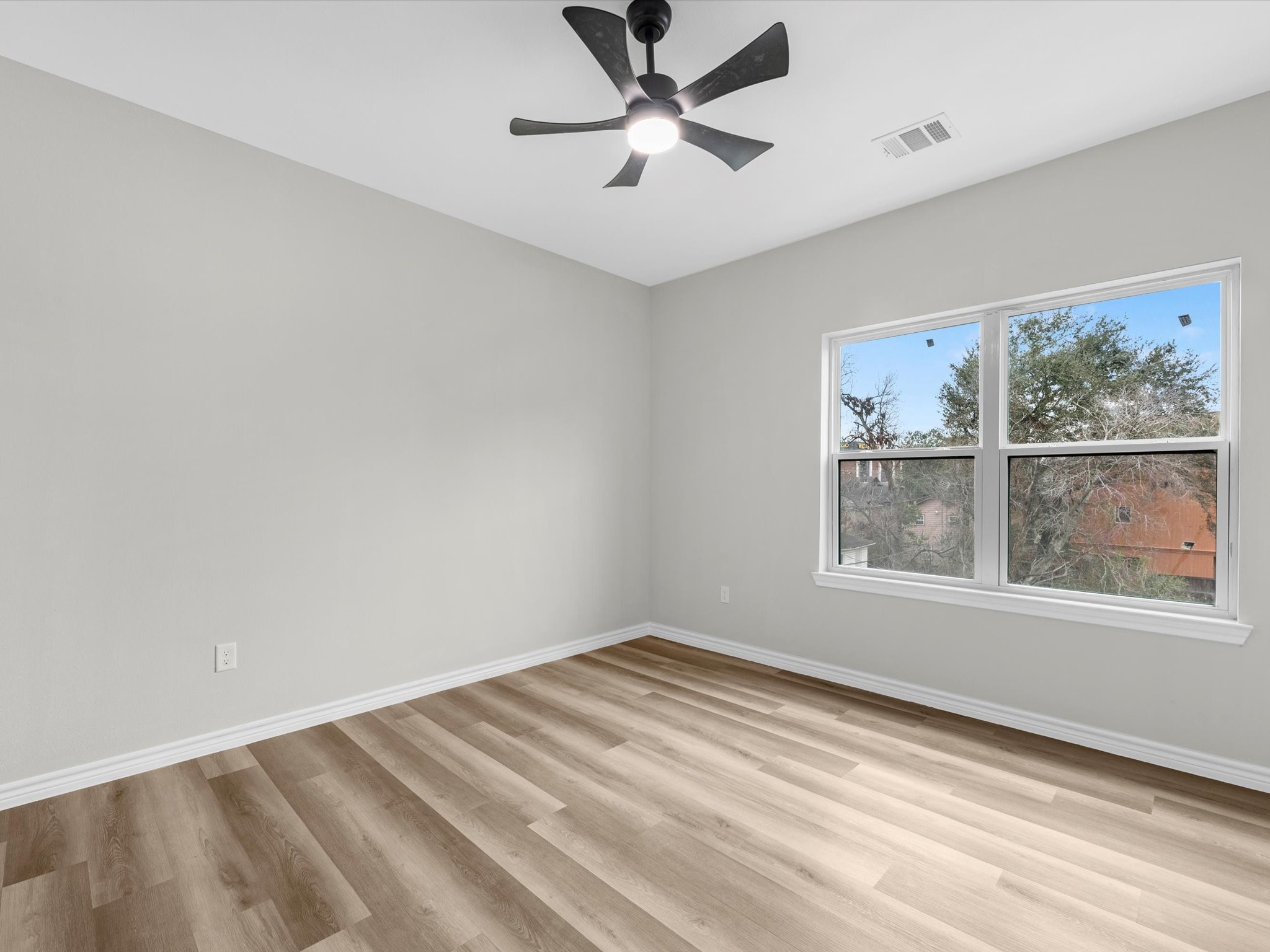 1319 West Bell Street Houston, TX 77019 - Photo 38 of 50 This room features fresh, neutral walls and vinyl flooring, creating a bright and airy space. It includes a modern ceiling fan and a large window, offering plenty of natural light and a view of greenery outside.